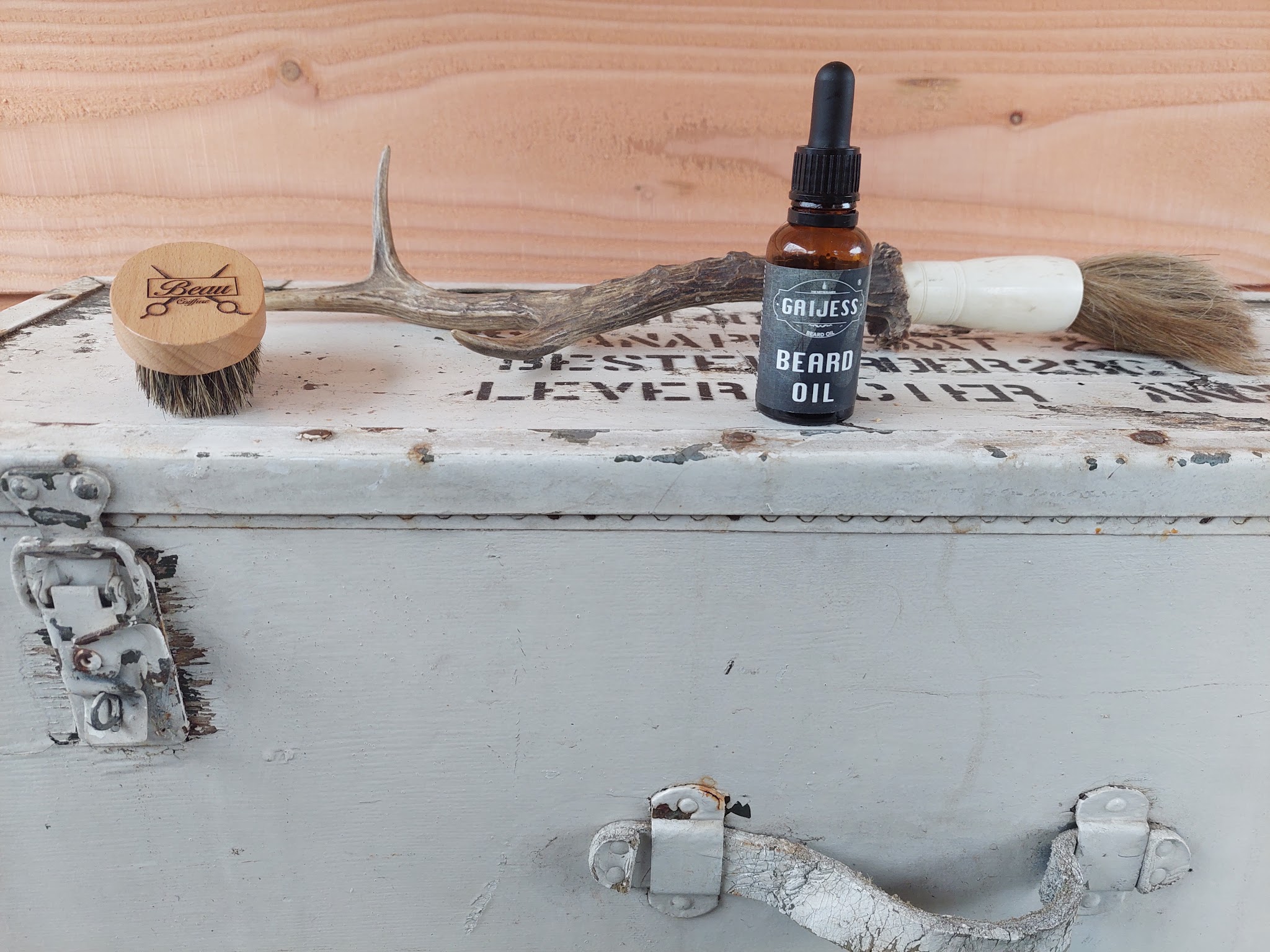 Gaijess beard oil, een baardborstel en een scheerkwast op een witte vintage koffer